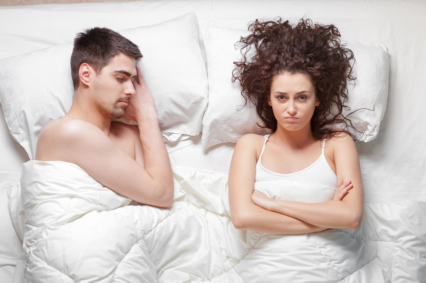 Overhead of young couple in the bed. Attractive woman is angy wi