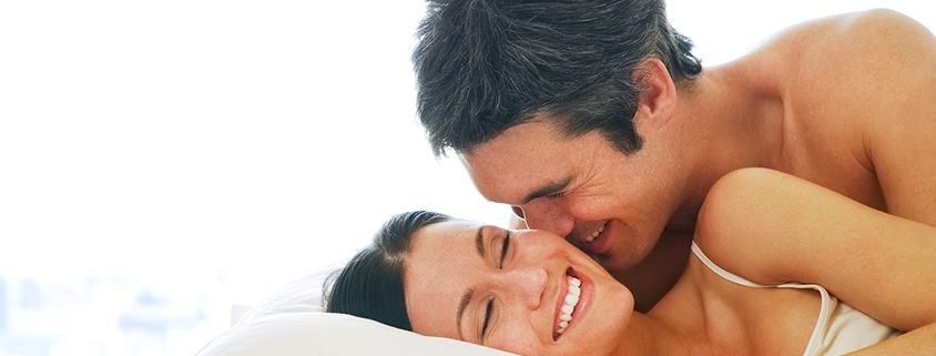 Young adult heterosexual couple lying on bed in bedroom